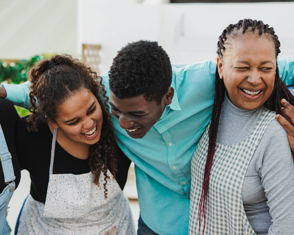 happy african family hugging each other at home - parents and adult children having fun together
