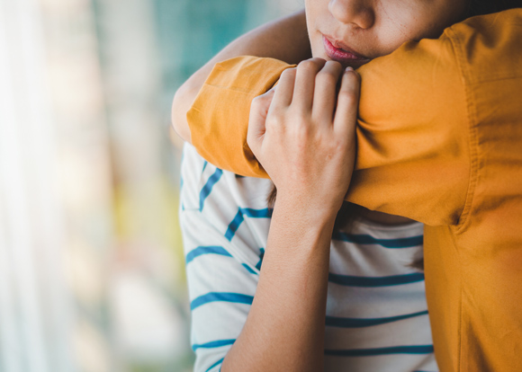 close up of hug between young adult and safe person supporting mental health