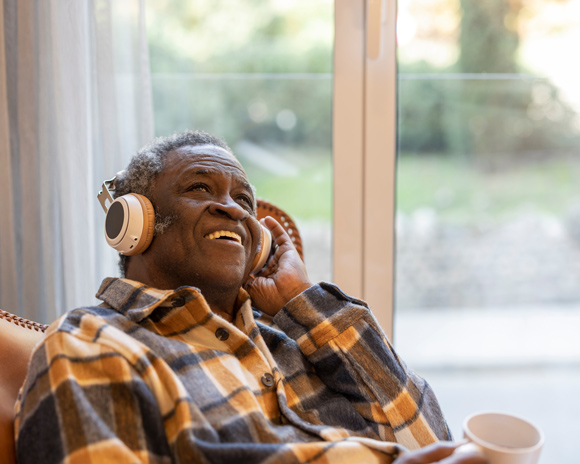 adult man listening to music in headphones at home with mug of tea